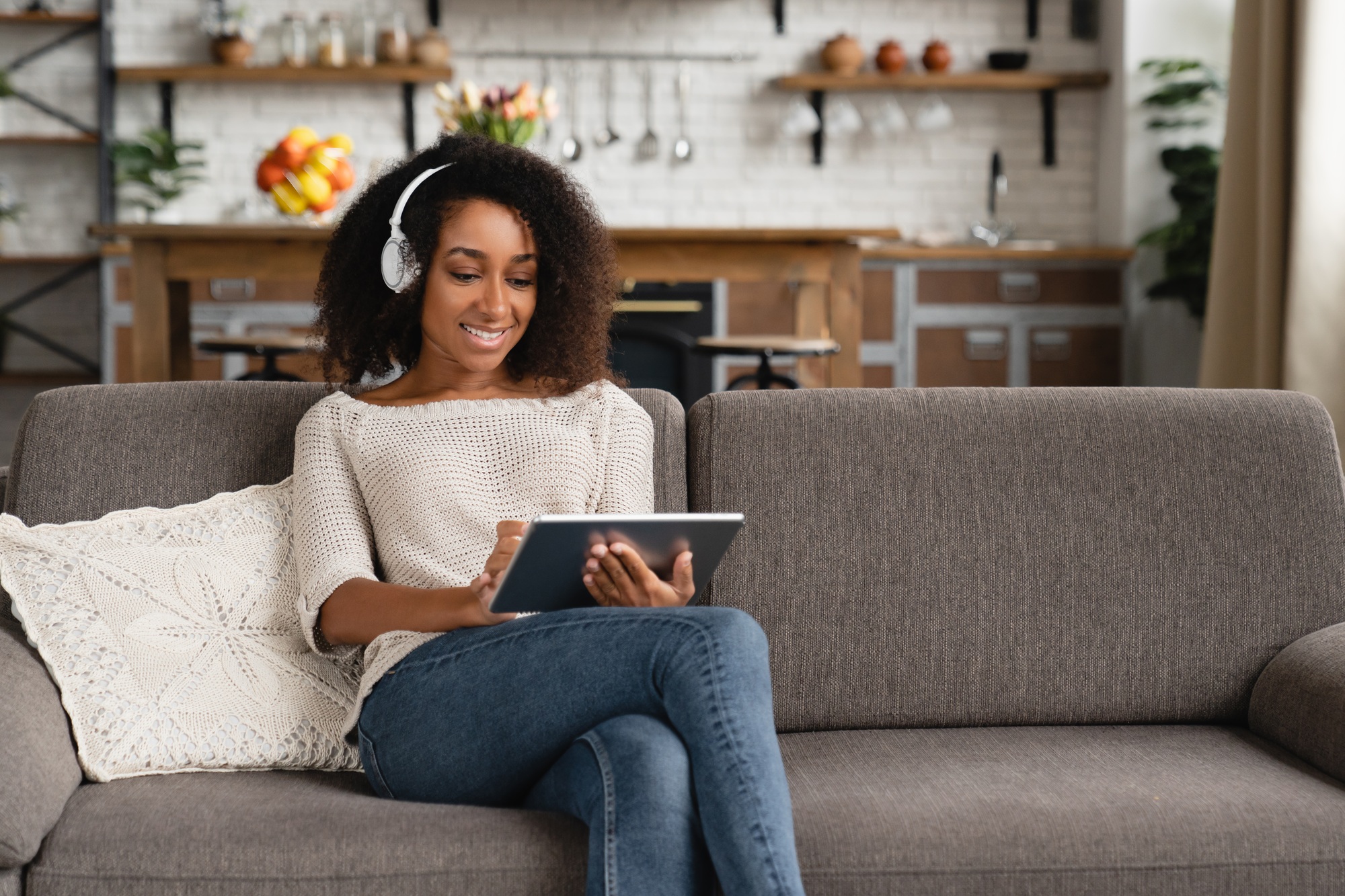 Girl with tablet, watching online webinar, listening to the music e-book podcast in headphones